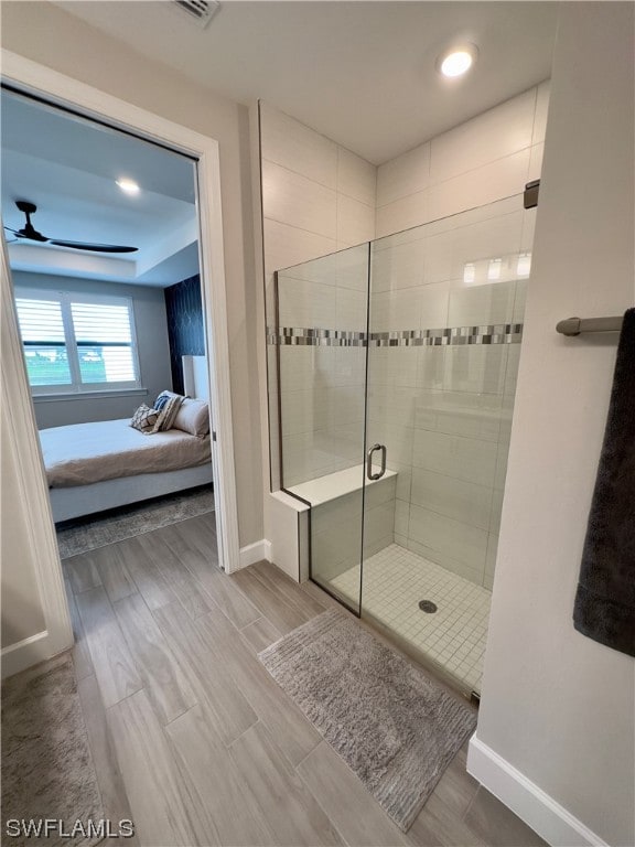 bathroom with a shower with shower door and ceiling fan