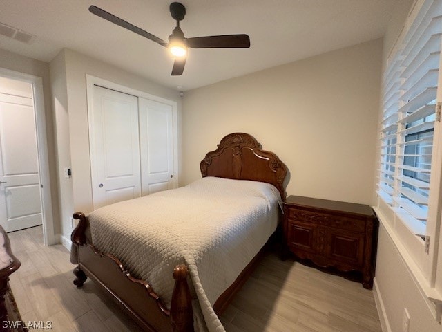 bedroom with light hardwood / wood-style flooring, ceiling fan, and a closet