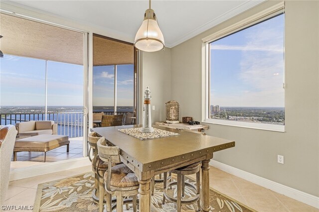 dining room featuring a water view, ornamental molding, and light tile floors