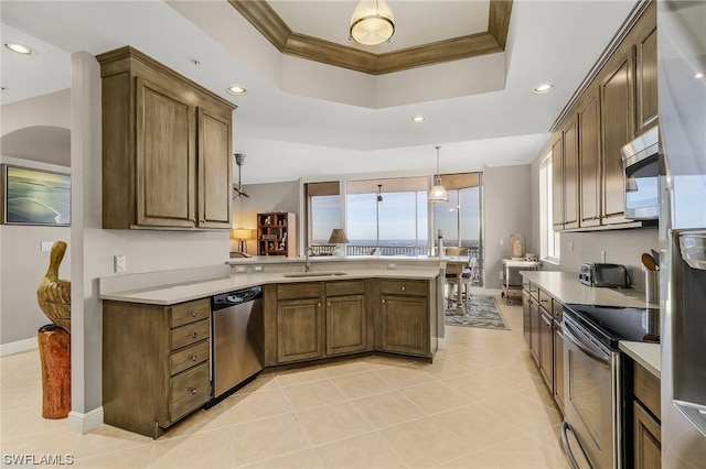 kitchen featuring pendant lighting, light tile flooring, kitchen peninsula, appliances with stainless steel finishes, and a raised ceiling