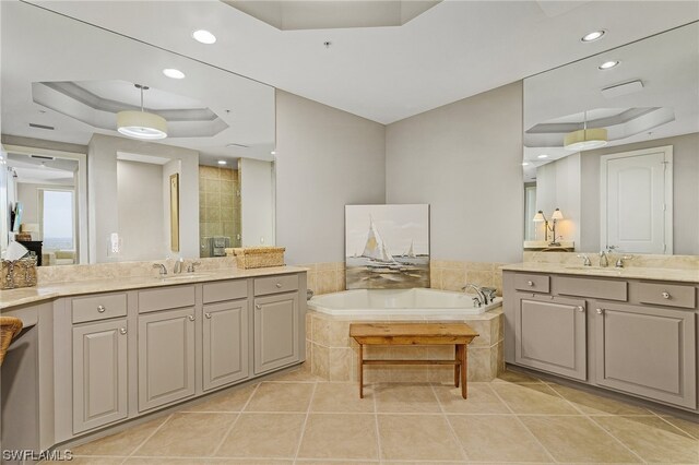 bathroom with vanity, tile floors, a raised ceiling, and tiled tub