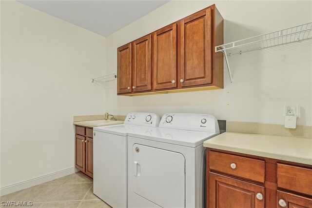 clothes washing area featuring separate washer and dryer, light tile floors, cabinets, and sink