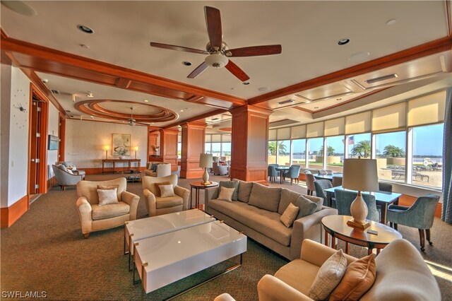 interior space featuring dark carpet, ceiling fan, a tray ceiling, and ornate columns