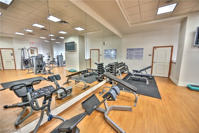 workout area featuring a drop ceiling and light wood-type flooring