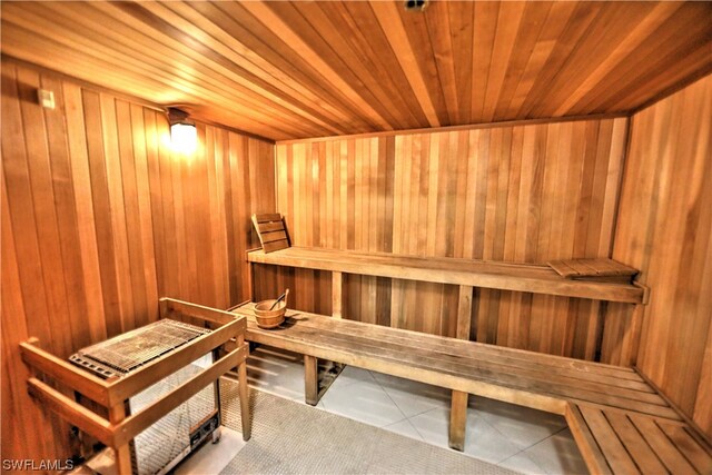 view of sauna / steam room featuring wooden ceiling, wood walls, and tile flooring