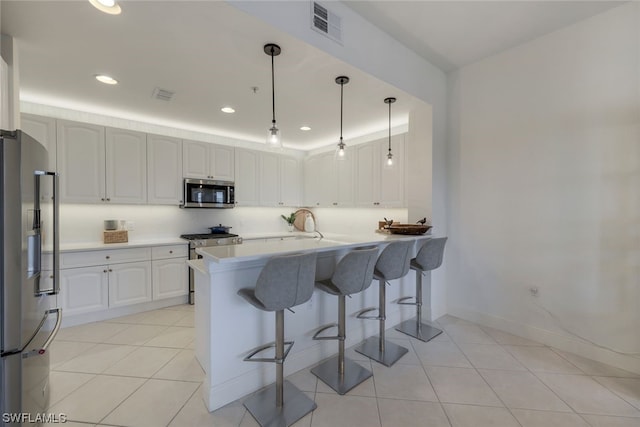 kitchen with appliances with stainless steel finishes, hanging light fixtures, white cabinets, and kitchen peninsula