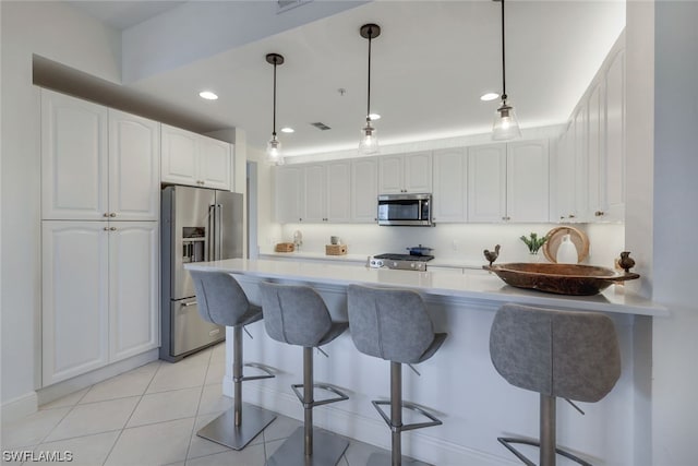 kitchen with stainless steel appliances, a breakfast bar area, and white cabinetry