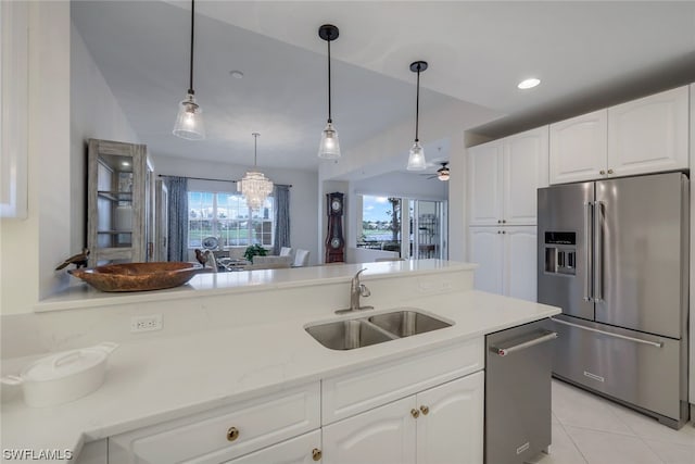 kitchen featuring stainless steel appliances, sink, white cabinetry, hanging light fixtures, and a chandelier