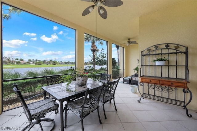 sunroom with ceiling fan and a water view