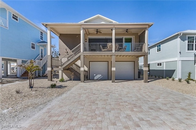 coastal home with covered porch, a garage, and ceiling fan