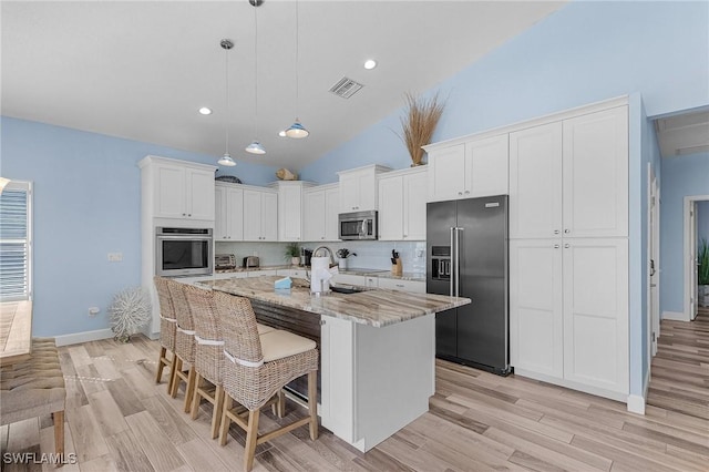 kitchen featuring white cabinetry, light stone countertops, pendant lighting, a center island with sink, and appliances with stainless steel finishes