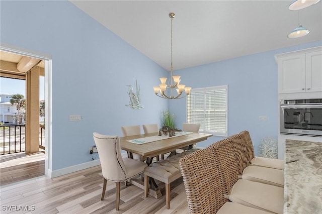 dining space with a healthy amount of sunlight, light wood-type flooring, an inviting chandelier, and lofted ceiling