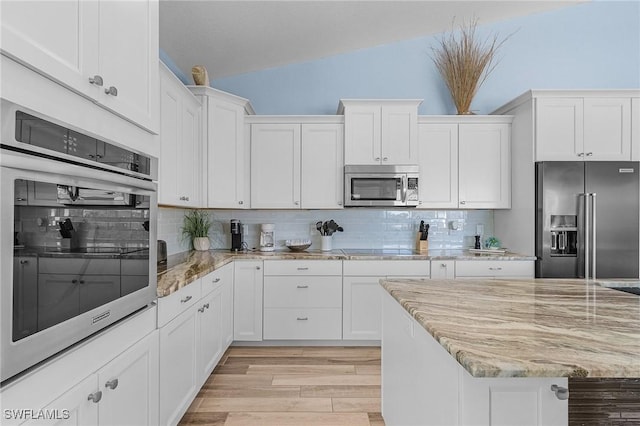 kitchen with backsplash, white cabinets, light wood-type flooring, appliances with stainless steel finishes, and light stone counters