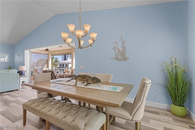 dining room with ceiling fan with notable chandelier, light hardwood / wood-style floors, and vaulted ceiling