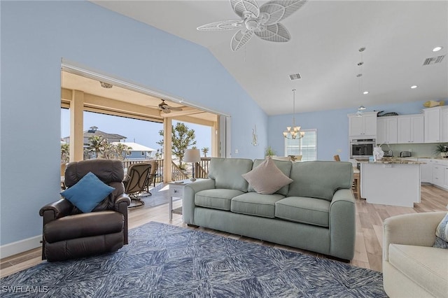 living room with ceiling fan with notable chandelier, hardwood / wood-style flooring, and lofted ceiling