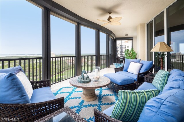 sunroom / solarium with plenty of natural light, ceiling fan, and a water view