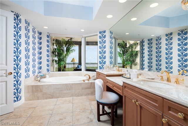 bathroom with vanity, a tray ceiling, and tiled tub