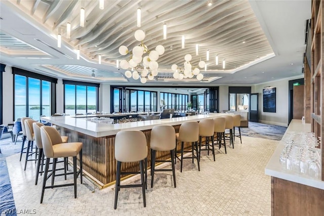 bar with crown molding, a chandelier, and a water view