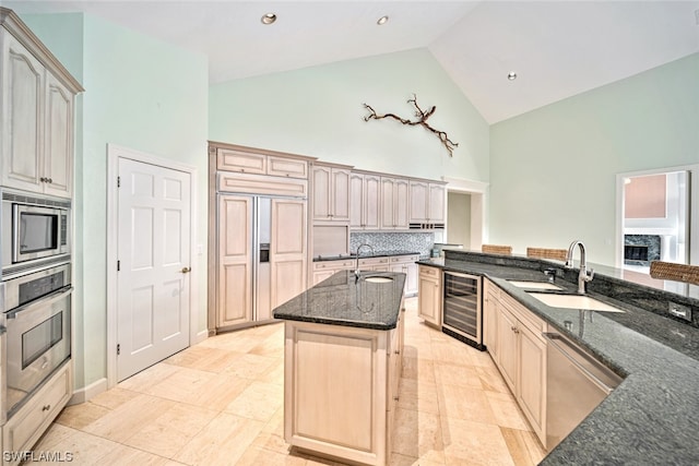 kitchen with high vaulted ceiling, sink, an island with sink, wine cooler, and built in appliances