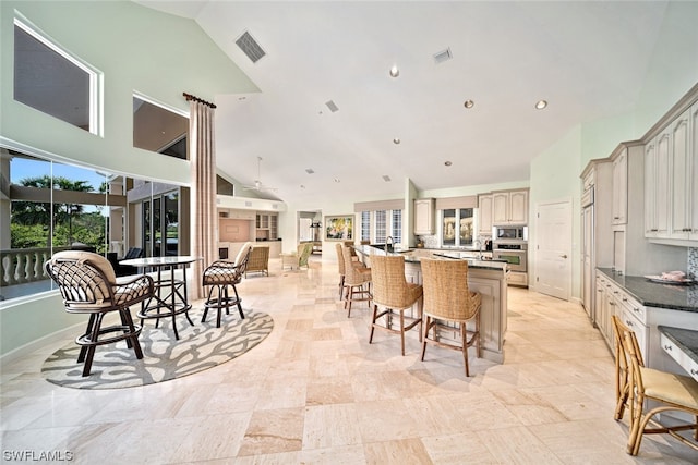 kitchen featuring a center island, high vaulted ceiling, light tile flooring, and stainless steel appliances