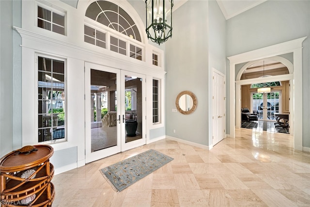 tiled foyer entrance with a healthy amount of sunlight, french doors, and an inviting chandelier