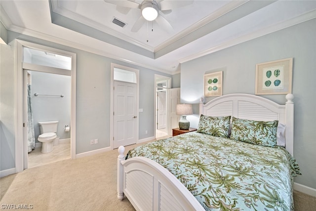 bedroom with light carpet, a tray ceiling, ceiling fan, and ensuite bathroom