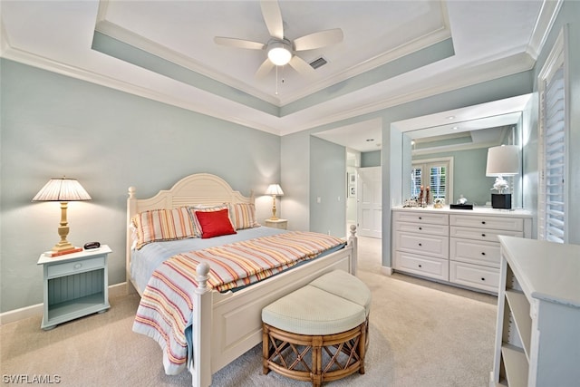 carpeted bedroom with a tray ceiling, ceiling fan, and ornamental molding