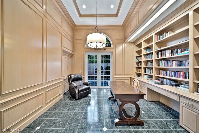 living area with french doors, dark tile flooring, a raised ceiling, ornamental molding, and built in desk