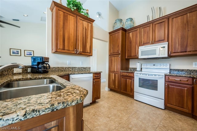 kitchen featuring high vaulted ceiling, light tile floors, white appliances, dark stone countertops, and sink