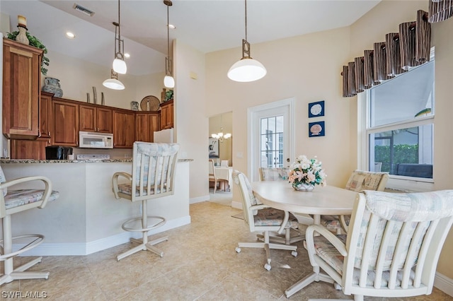 dining area featuring light tile floors, a towering ceiling, and an inviting chandelier