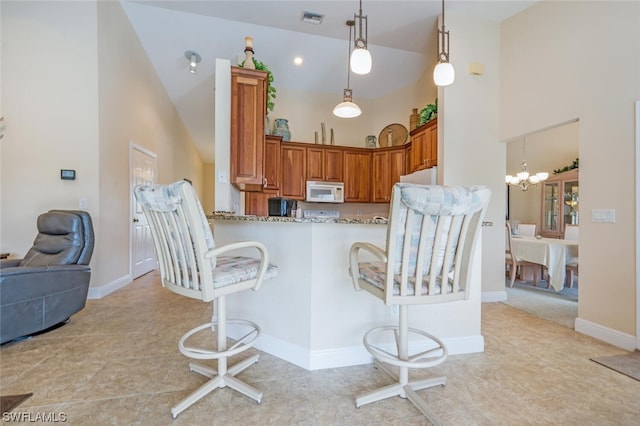 kitchen with kitchen peninsula, light tile floors, high vaulted ceiling, decorative light fixtures, and a notable chandelier