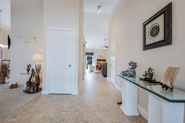 hallway featuring light tile flooring and a towering ceiling