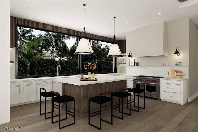 kitchen featuring a breakfast bar area, white cabinets, hardwood / wood-style floors, and designer stove