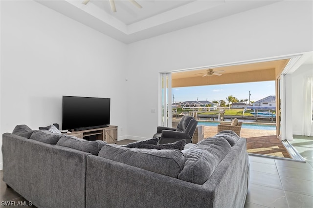 living room with ceiling fan, a towering ceiling, and tile flooring