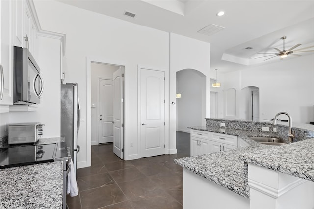 kitchen with appliances with stainless steel finishes, ceiling fan, white cabinetry, sink, and pendant lighting