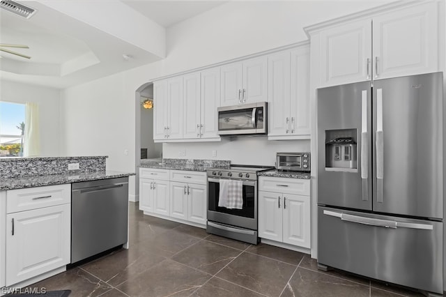 kitchen featuring appliances with stainless steel finishes, dark tile flooring, and white cabinets