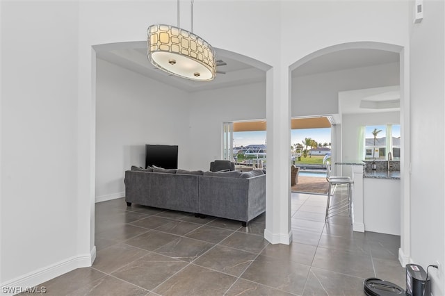 living room featuring dark tile floors, a raised ceiling, and a high ceiling