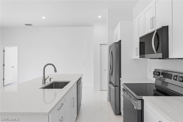 kitchen featuring stainless steel appliances, sink, light stone countertops, white cabinets, and light tile patterned floors