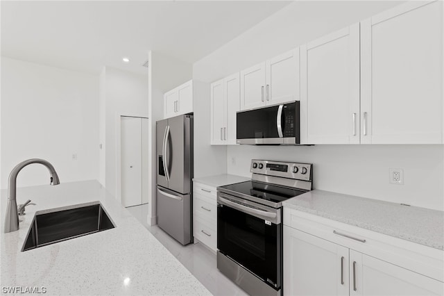 kitchen with sink, white cabinets, light stone countertops, and stainless steel appliances