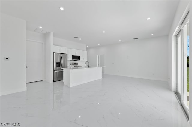 kitchen with sink, white cabinetry, an island with sink, light tile patterned floors, and stainless steel appliances