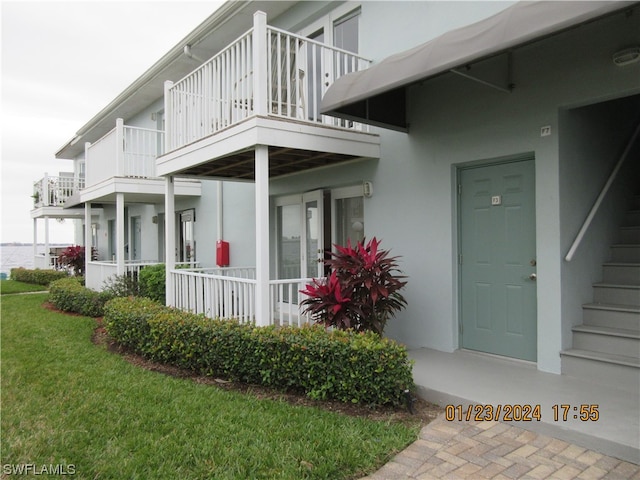 property entrance featuring a balcony and a yard