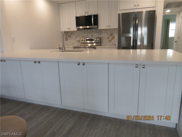 kitchen with stainless steel appliances, dark hardwood / wood-style flooring, white cabinets, backsplash, and sink