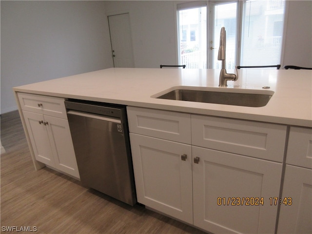 kitchen featuring sink, white cabinetry, stainless steel dishwasher, and hardwood / wood-style flooring