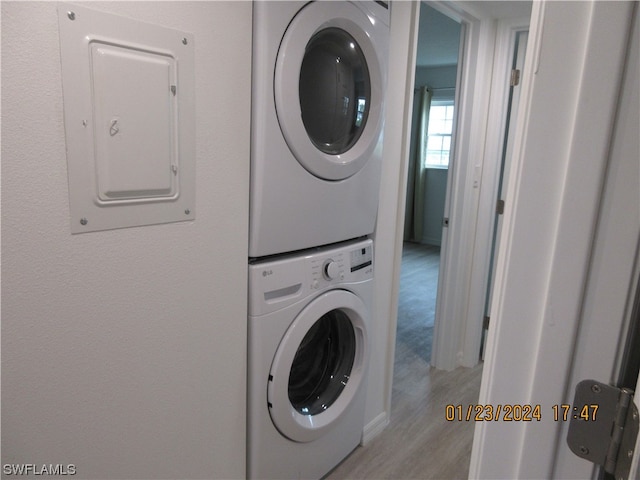 laundry room featuring stacked washer and clothes dryer and light wood-type flooring