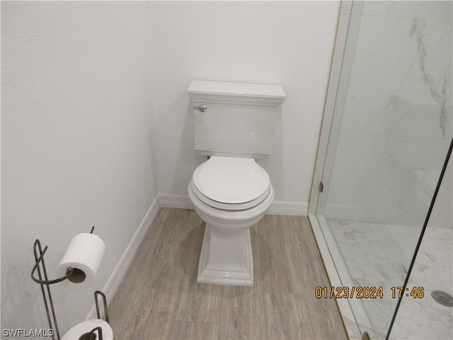 bathroom featuring toilet, hardwood / wood-style floors, and a shower with shower door