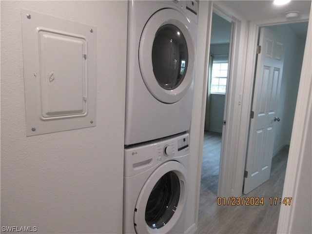 laundry room with stacked washing maching and dryer and hardwood / wood-style flooring