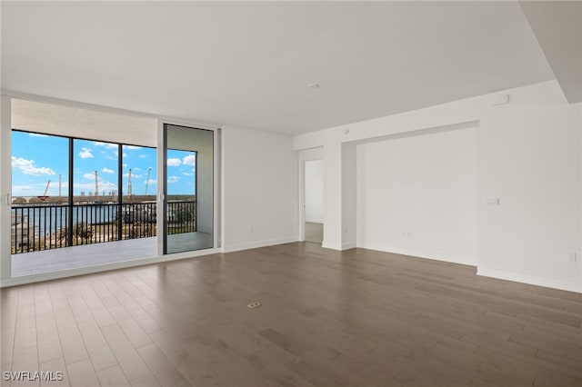 unfurnished room with a wall of windows, baseboards, and wood finished floors