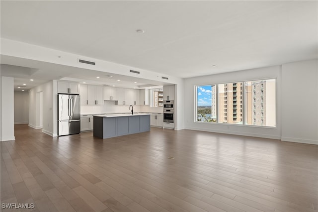 unfurnished living room featuring baseboards, visible vents, dark wood finished floors, a sink, and recessed lighting