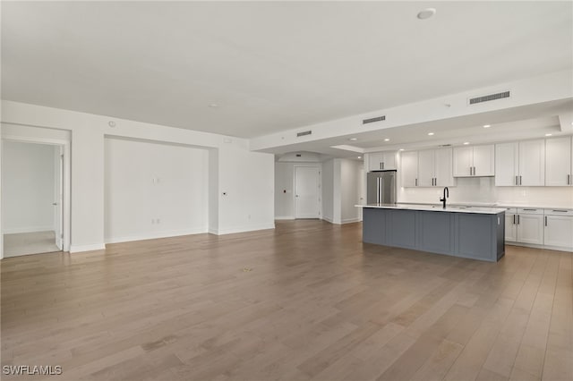 kitchen featuring visible vents, open floor plan, white cabinetry, high quality fridge, and a sink