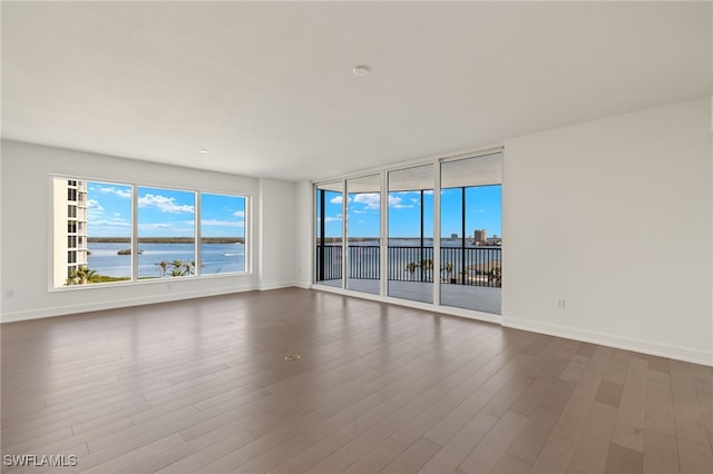 empty room with a water view, baseboards, and dark wood-style flooring